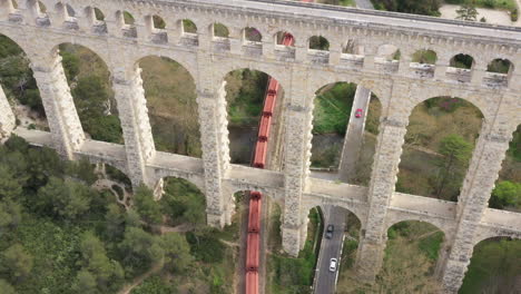 Cargo-train-passing-under-the-bridge-aqueduct-de-roquefavour-France-aerial-view